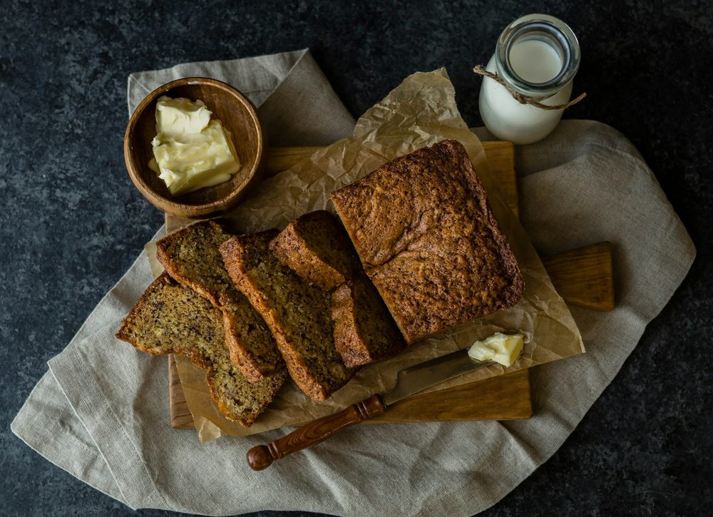 Gluten-free banana bread loaf with slices on board and butter